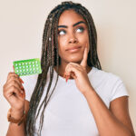 Young,African,American,Woman,With,Braids,Holding,Birth,Control,Pills
