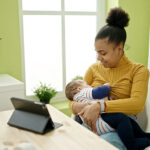 Mother,And,Son,Using,Touchpad,Breastfeeding,Baby,At,Dinning,Room